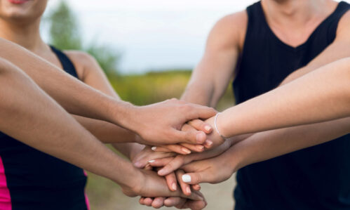 Eine Gruppe Menschen hält die Hände zusammen, verbinden sich, arbeiten Hand in Hand.